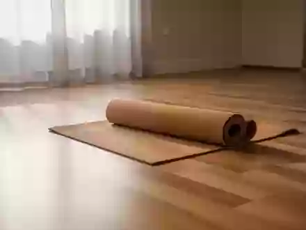 Ein minimalistischer, heller Yoga-Raum mit einer einzelnen Kork-Yogamatte auf einem Holzboden in natürlichem Licht. - Foto: über boerse-global.de