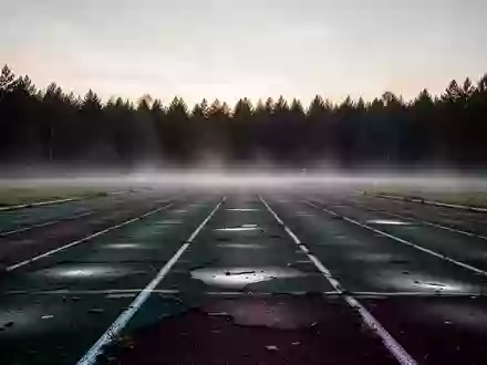 Eine leere, morgendliche Sportlaufbahn im Nebel als Symbol für die Risiken von Übertraining. - Foto: über boerse-global.de