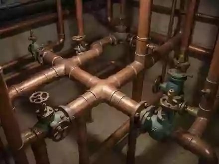 Nahaufnahme eines komplexen Systems aus alten Wasserrohren und Ventilen in einem dunklen Kellerraum. - Foto: über boerse-global.de