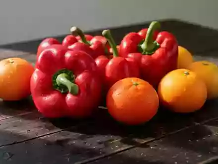 Frische rote Paprika und Zitrusfrüchte auf einem rustikalen Holztisch bei natürlichem Tageslicht. - Foto: über boerse-global.de