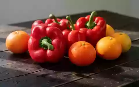 Frische rote Paprika und Zitrusfrüchte auf einem rustikalen Holztisch bei natürlichem Tageslicht. - Foto: über boerse-global.de