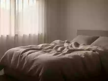 Ein minimalistisch gestaltetes Schlafzimmer mit weichem Tageslicht und ungemachtem Bett in ruhiger Atmosphäre. - Foto: über boerse-global.de