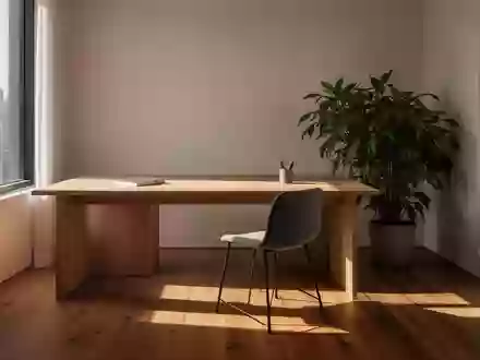 Ein minimalistischer, lichtdurchfluteter Arbeitsbereich mit einem Holztisch und einer Pflanze vor einem Fenster. - Foto: über boerse-global.de