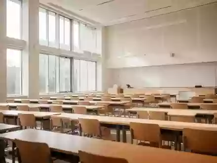 Ein heller, moderner Hörsaal mit leeren Holztischen und Stühlen in einer Universität. - Foto: über boerse-global.de