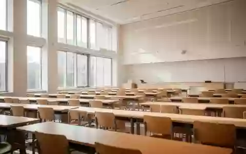 Ein heller, moderner Hörsaal mit leeren Holztischen und Stühlen in einer Universität. - Foto: über boerse-global.de