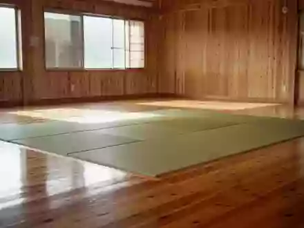 Ein heller, minimalistischer Trainingsraum für Kampfkünste mit poliertem Holzboden und einer leeren Tatami-Mattenfläche. - Foto: über boerse-global.de