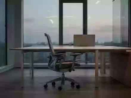 Ein leerer, minimalistischer Büroarbeitsplatz mit einem einzelnen Bürostuhl vor einem aufgeräumten Schreibtisch bei Dämmerung. - Foto: über boerse-global.de