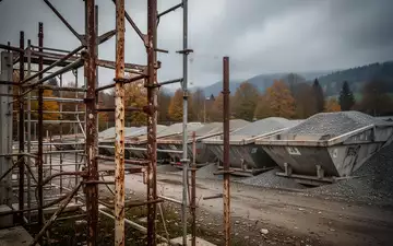 Leere Baustelle an einem Kieswerk mit Gerüstteilen unter einem bewölkten Himmel. - Foto: über boerse-global.de