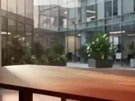 Ein minimalistischer, moderner Arbeitsplatz mit warmem Tageslicht auf einer Holzoberfläche und einem unscharfen Bürogebäude im Hintergrund. - Foto: über boerse-global.de