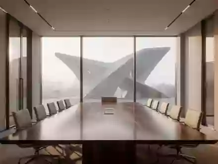 Ein moderner, minimalistischer Konferenzraum mit einem großen Holztisch und leeren Stühlen in hellem Tageslicht. - Foto: über boerse-global.de