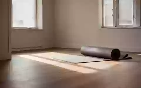 Ein sonnendurchfluteter, minimalistischer Raum mit einem aufgerollten Yogamatte auf einem Holzboden. - Foto: über boerse-global.de