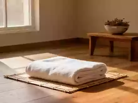 Ein minimalistischer Wellness-Raum mit einem gefalteten Baumwollhandtuch auf einer Bambusmatte in natürlichem Sonnenlicht. - Foto: über boerse-global.de
