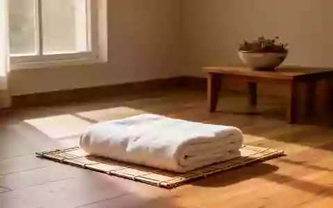 Ein minimalistischer Wellness-Raum mit einem gefalteten Baumwollhandtuch auf einer Bambusmatte in natürlichem Sonnenlicht. - Foto: über boerse-global.de