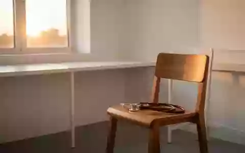 Ein minimalistisch eingerichteter Untersuchungsraum mit einem Stethoskop auf einem Holzstuhl in warmem Licht. - Foto: über boerse-global.de