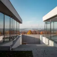 Moderne Industriearchitektur mit Glasfassaden und Windrädern in einer weiten deutschen Landschaft bei hellem Tageslicht. - Foto: über boerse-global.de