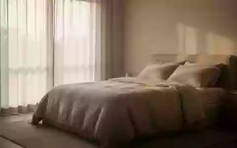Ein minimalistisch eingerichtetes Schlafzimmer mit weichem Tageslicht und einem ordentlich gemachten Bett. - Foto: über boerse-global.de