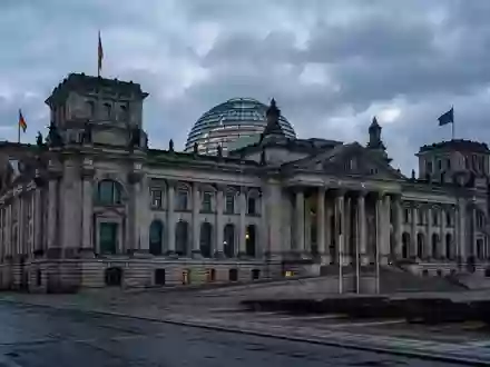 Das Berliner Reichstagsgebäude in der Abenddämmerung bei bewölktem Himmel. - Foto: über boerse-global.de