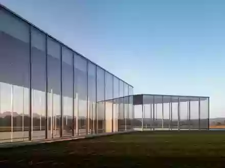 Ein minimalistisches, modernes Bürogebäude aus Glas vor einem weiten, klaren Himmel bei natürlichem Licht. - Foto: über boerse-global.de