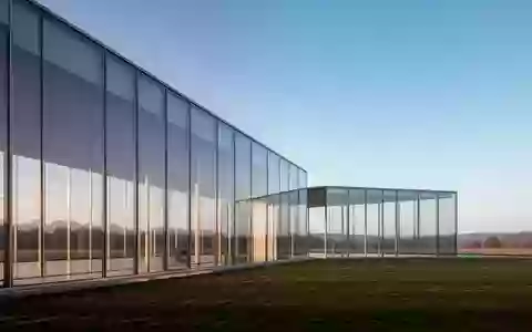 Ein minimalistisches, modernes Bürogebäude aus Glas vor einem weiten, klaren Himmel bei natürlichem Licht. - Foto: über boerse-global.de