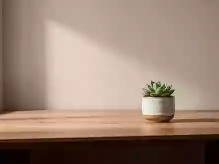 Ein minimalistischer, aufgeräumter Arbeitsplatz mit einem hölzernen Schreibtisch, einer kleinen Pflanze und natürlichem Licht. - Foto: über boerse-global.de