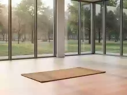 Ein heller, minimalistischer Übungsraum mit Holzboden und Blick auf einen grünen Park, in dem eine einzelne Yogamatte liegt. - Foto: über boerse-global.de