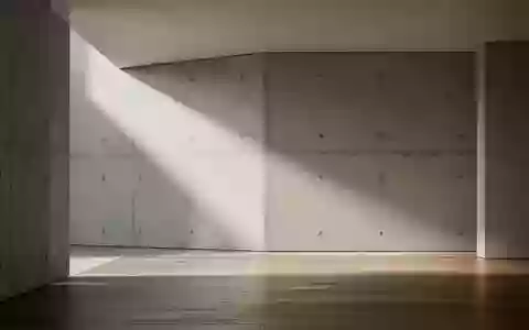 Ein minimalistischer, moderner Innenraum mit klaren geometrischen Linien und natürlichem Lichteinfall auf Beton und Holz. - Foto: über boerse-global.de