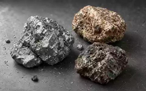Nahaufnahme von rauen, industriellen Seltene-Erden-Mineralproben auf einer dunklen Werkbank bei natürlichem Licht. - Foto: über boerse-global.de