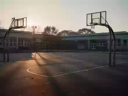 Ein leerer Schulhof mit Basketballkorb in der Dämmerung, der die Stille und die gesundheitliche Thematik symbolisiert. - Foto: über boerse-global.de