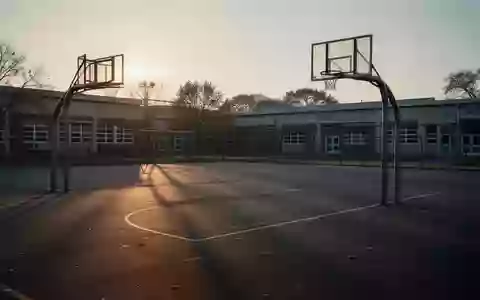 Ein leerer Schulhof mit Basketballkorb in der Dämmerung, der die Stille und die gesundheitliche Thematik symbolisiert. - Foto: über boerse-global.de