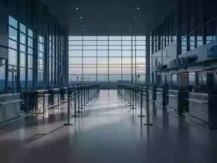 Leerer Check-in-Bereich eines Flughafens mit langen, unbesetzten Schaltern in kühlem, natürlichem Licht. - Foto: über boerse-global.de