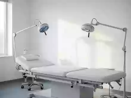 Ein minimalistischer, heller medizinischer Behandlungsraum mit einer Untersuchungsliege und einer Diagnostikleuchte. - Foto: über boerse-global.de