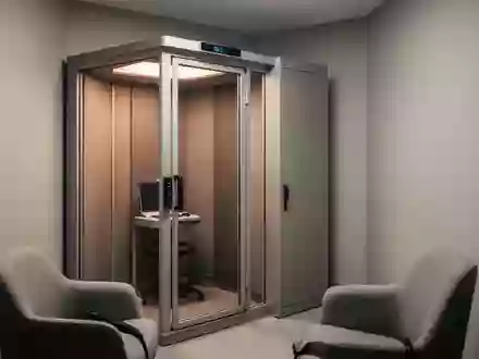 Ein heller, minimalistischer Behandlungsraum in einer audiologischen Fachpraxis mit einer schallisolierten Kabine. - Foto: über boerse-global.de