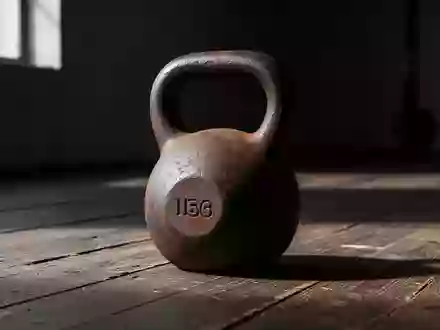 Eine schwere gusseiserne Kettlebell auf einem abgenutzten Holzboden in einem minimalistisch beleuchteten Raum. - Foto: über boerse-global.de