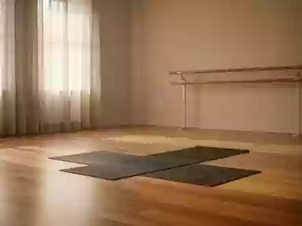 Ein minimalistisch eingerichteter Yogaraum mit Holzboden, einer Ballettstange an der Wand und weichem Tageslicht. - Foto: über boerse-global.de