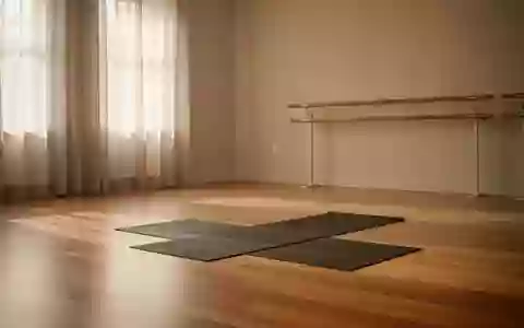 Ein minimalistisch eingerichteter Yogaraum mit Holzboden, einer Ballettstange an der Wand und weichem Tageslicht. - Foto: über boerse-global.de