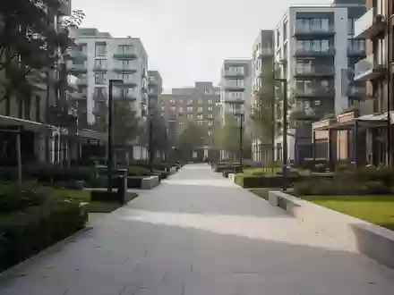 Ein moderner, gepflasterter Fußgängerweg in einer britischen Stadt mit Grünflächen und moderner Architektur im Hintergrund. - Foto: über boerse-global.de