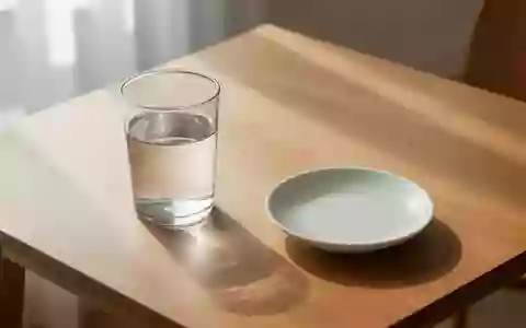 Ein Glas mit klarem Wasser auf einem schlichten Holztisch in einem hellen Raum. - Foto: ĂŒber boerse-global.de