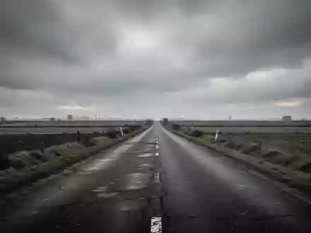 Eine leere Landstraße in einer europäischen Landschaft bei bewölktem Himmel. - Foto: über boerse-global.de