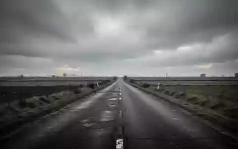 Eine leere Landstraße in einer europäischen Landschaft bei bewölktem Himmel. - Foto: über boerse-global.de