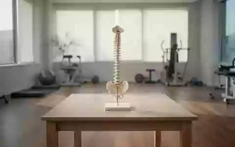 Ein minimalistischer, heller Behandlungsraum mit einem anatomischen Wirbelsäulenmodell auf einem Holztisch. - Foto: über boerse-global.de