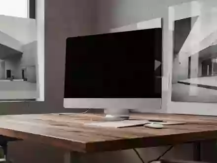 Ein minimalistischer Arbeitsplatz mit einem ausgeschalteten Monitor und natürlichem Licht, das auf eine Holzoberfläche fällt. - Foto: über boerse-global.de