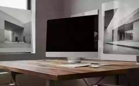 Ein minimalistischer Arbeitsplatz mit einem ausgeschalteten Monitor und natürlichem Licht, das auf eine Holzoberfläche fällt. - Foto: über boerse-global.de