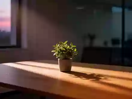 Ein minimalistischer, ruhiger Arbeitsplatz in der Abenddämmerung mit einer kleinen Pflanze auf einem leeren Holztisch. - Foto: über boerse-global.de