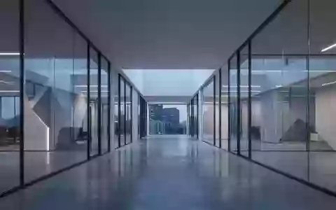 Ein minimalistischer, moderner Büroflur mit Glaswänden und reflektierenden Böden in der Abenddämmerung. - Foto: über boerse-global.de