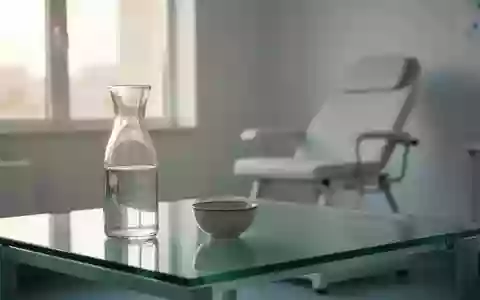 Ein minimalistischer, heller Behandlungsraum in einer Arztpraxis mit einem leeren Glastisch und einer Wasserkaraffe. - Foto: über boerse-global.de
