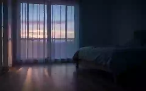 Ein minimalistisch eingerichtetes, in blaues Dämmerlicht getauchtes Schlafzimmer kurz vor Sonnenaufgang. - Foto: über boerse-global.de