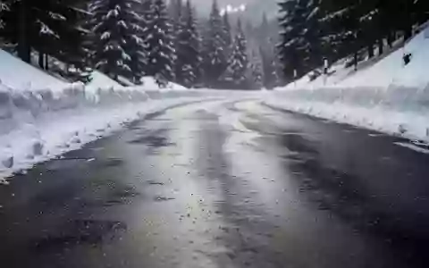 Verschneite Bergstraße mit winterlichen Fahrbahnverhältnissen in einer alpinen Landschaft. - Foto: über boerse-global.de