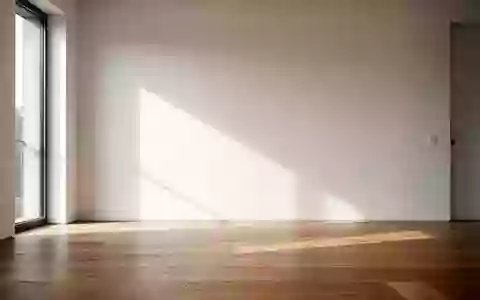 Ein minimalistischer, lichtdurchfluteter Raum mit Holzboden und einer leeren weißen Wand bei natürlichem Tageslicht. - Foto: über boerse-global.de