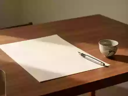 Ein minimalistischer Holztisch mit einem leeren Blatt Papier, einem Füllfederhalter und einer japanischen Teetasse bei Tageslicht. - Foto: über boerse-global.de