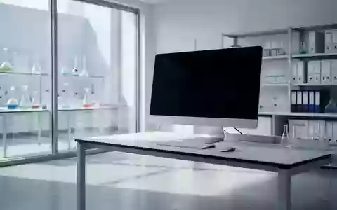 Ein minimalistisches, helles Labor mit einem ausgeschalteten Computerbildschirm und wissenschaftlichen Glasgeräten im Hintergrund. - Foto: über boerse-global.de